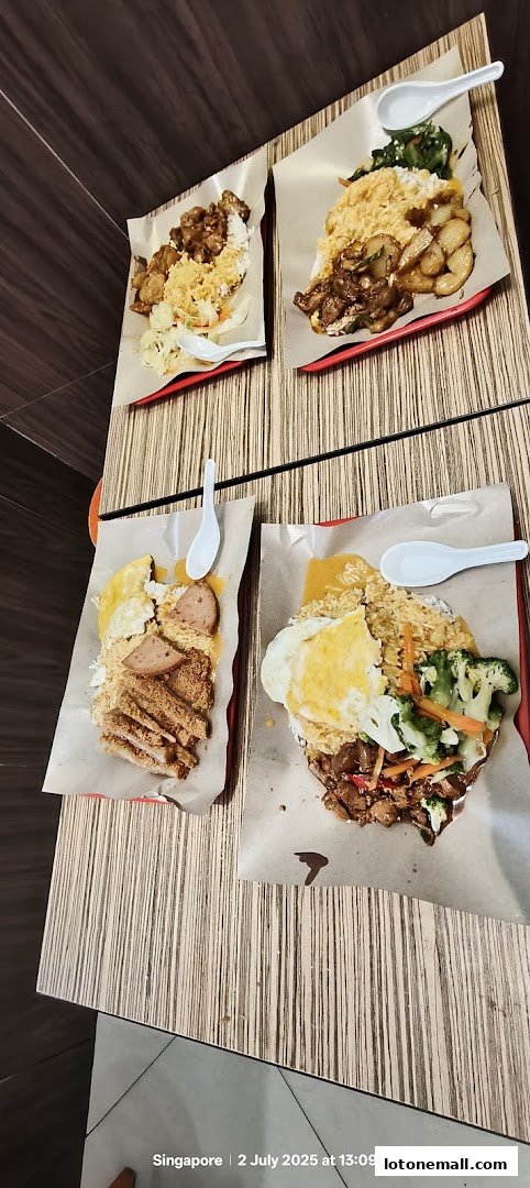 Four plates of Hainanese curry rice with various toppings and a spoon on each plate.
