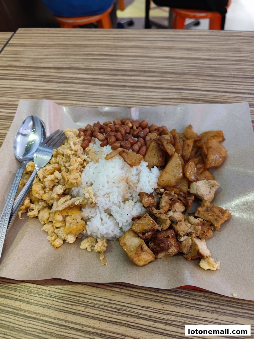 A plate of Hainanese curry rice with scrambled eggs, peanuts, and fried chicken.