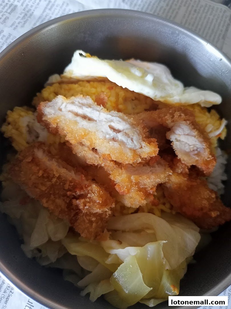 A close-up shot of Hainanese curry rice with fried chicken, a fried egg, and cabbage.