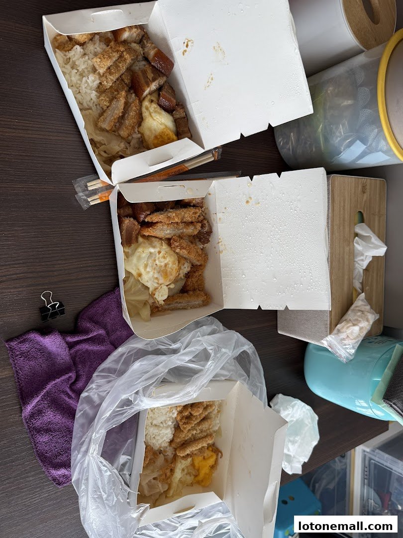 Three takeaway boxes of Hainanese curry rice with fried chicken and egg.