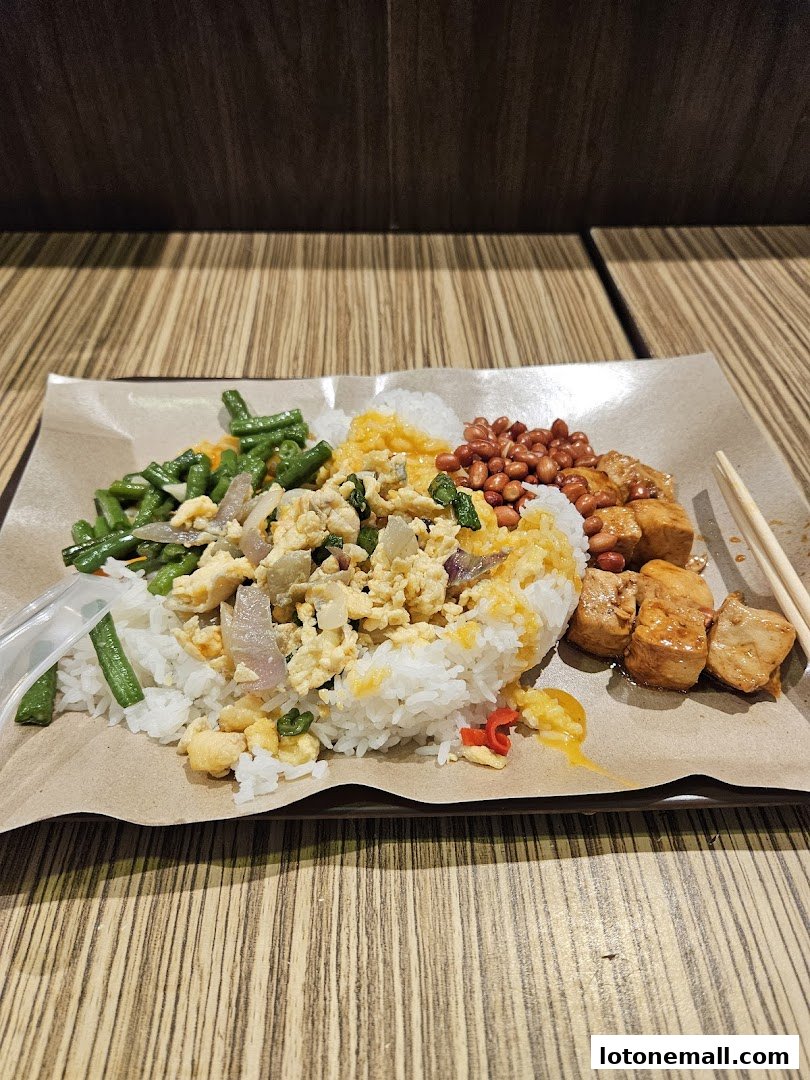 A plate of Hainanese curry rice with various toppings and a side of peanuts.