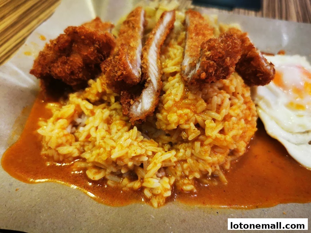 A close-up of Hainanese curry rice with fried chicken and a sunny-side-up egg.