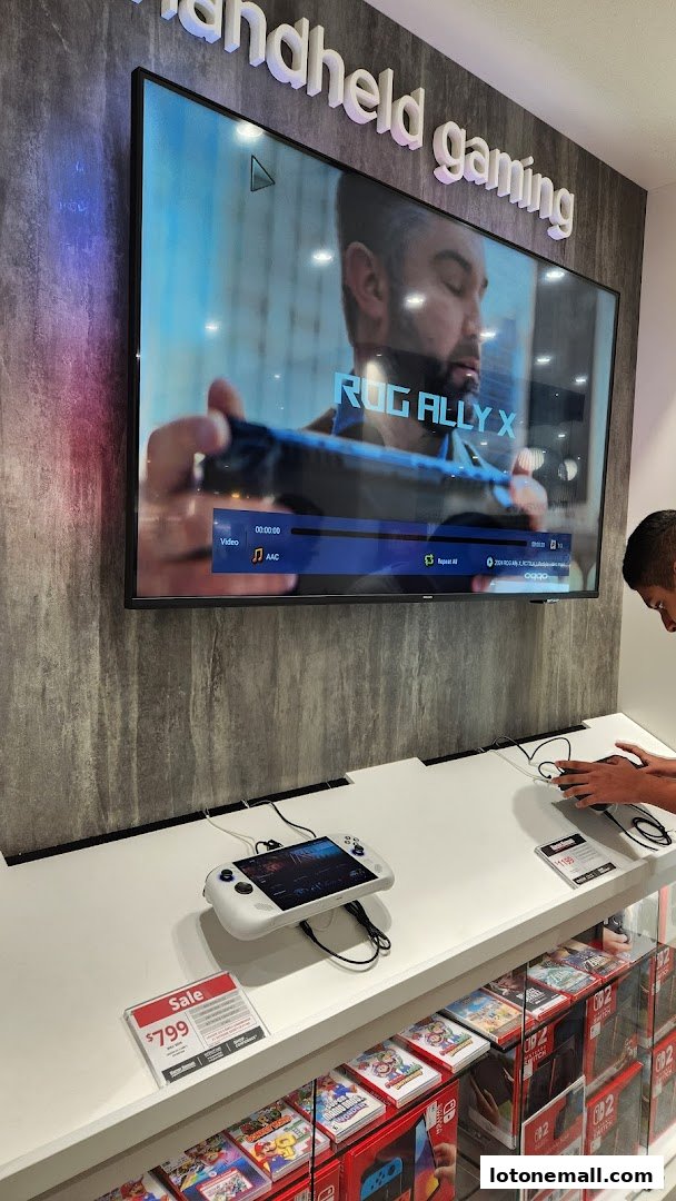 A display of handheld gaming devices and Nintendo Switch games with a promotional sign.