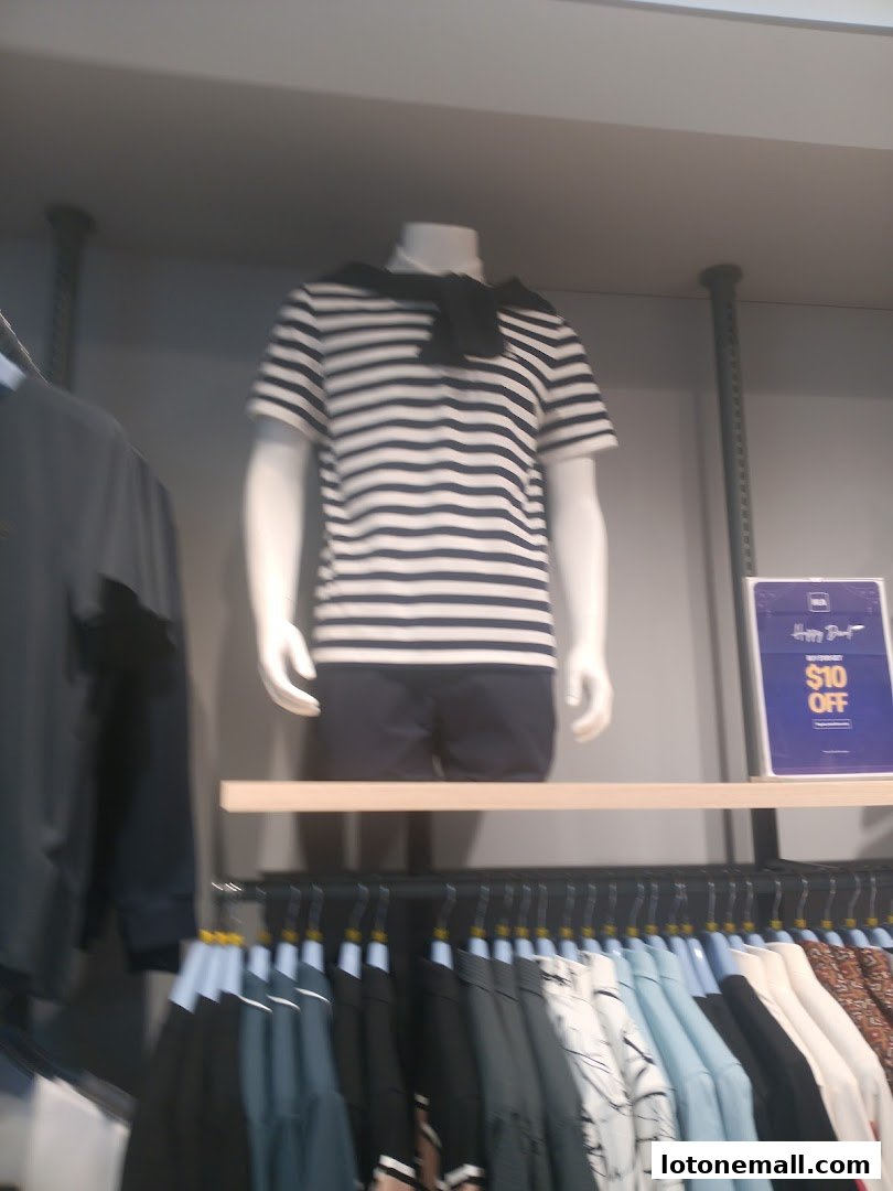 Mannequin wearing a striped t-shirt and shorts, with clothes on racks below.