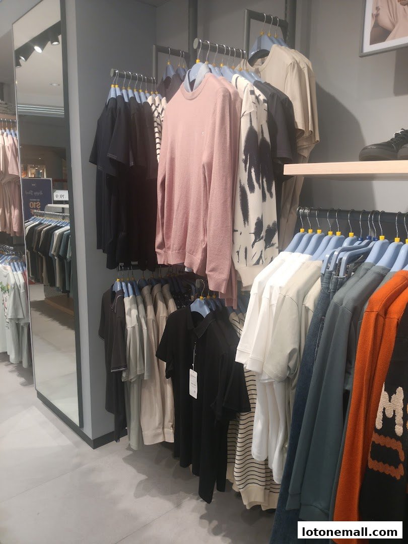 A clothing store interior with racks of t-shirts and sweaters in various colors and styles.