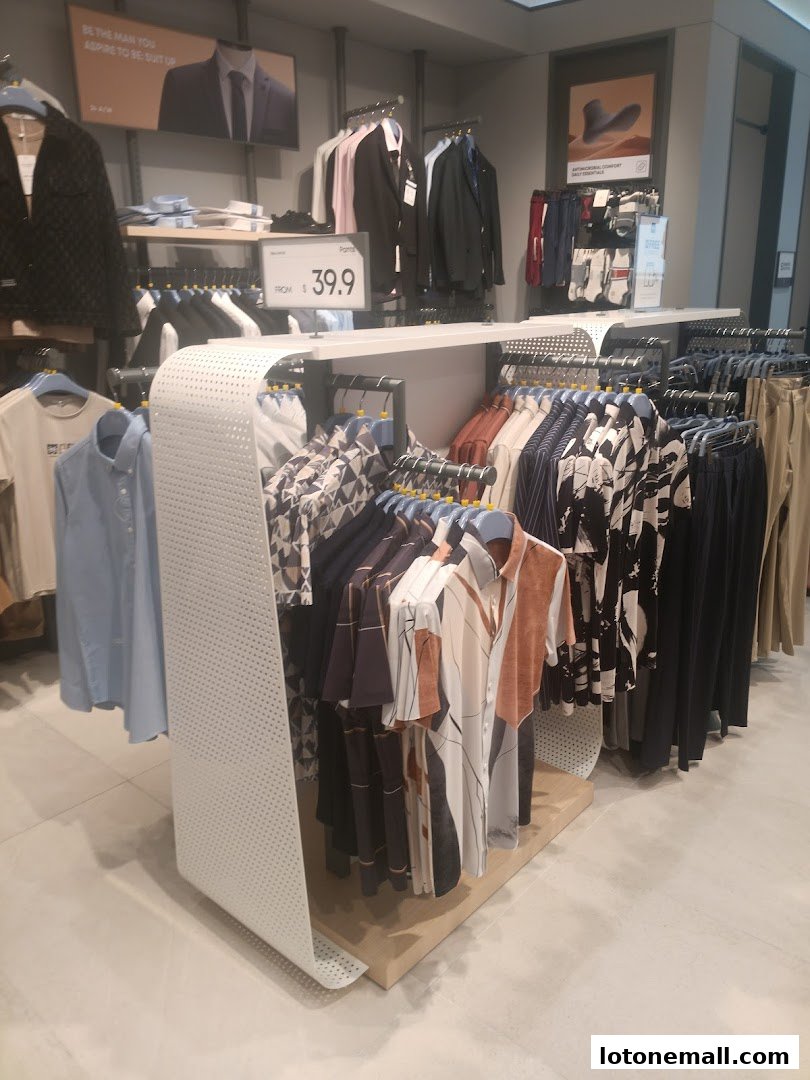 A well-lit retail store interior showcasing a variety of men's shirts and suits on display.