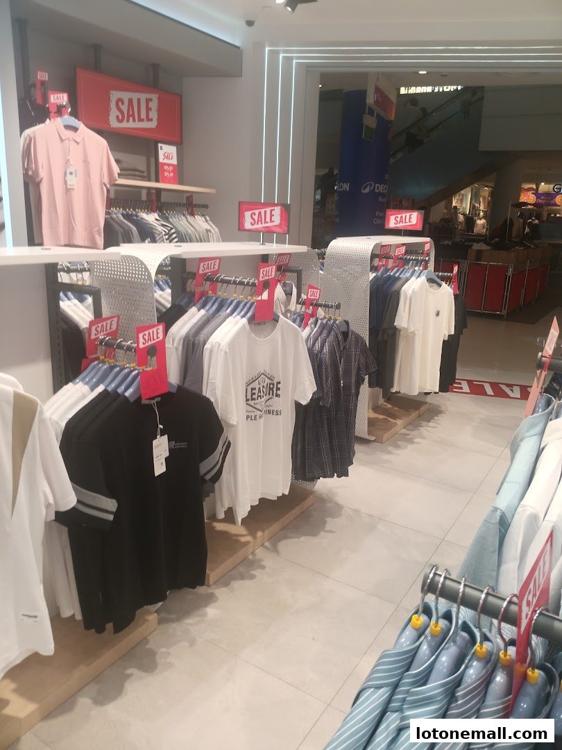 A clothing store interior with racks of shirts and sale signs.