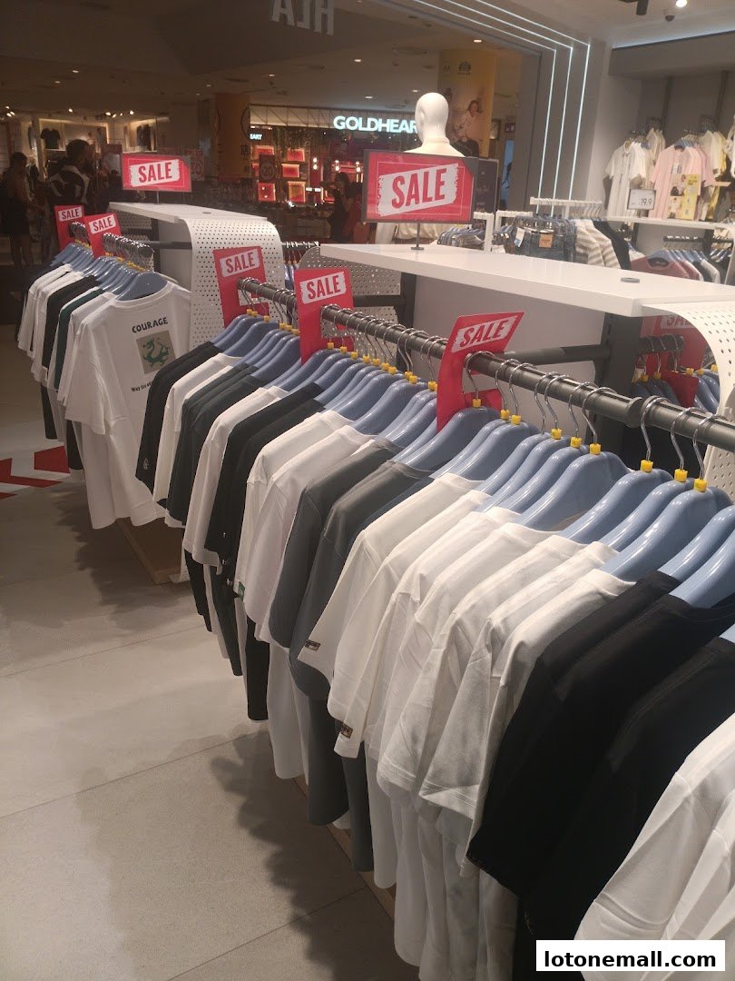 A clothing store interior with racks of t-shirts on sale.