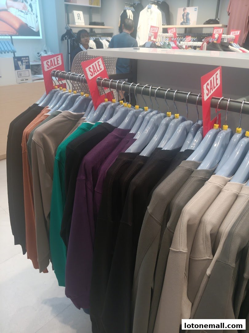 A rack of colorful sweaters with 'SALE' signs in a retail store.