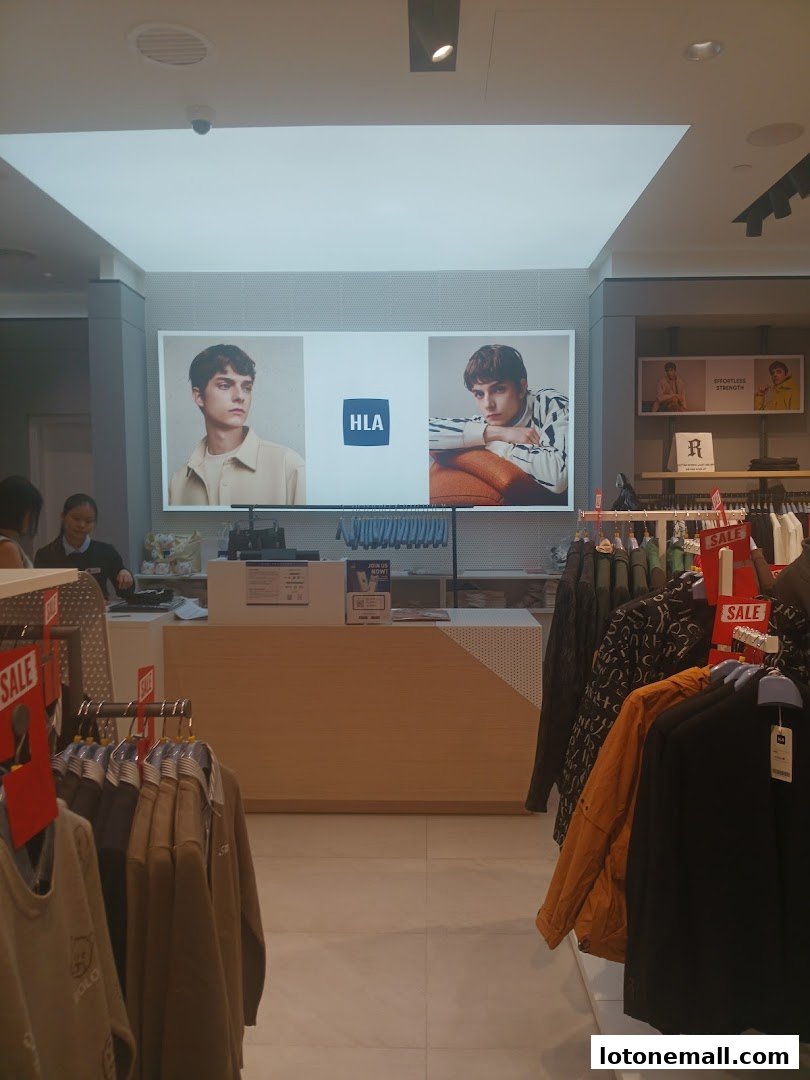 Interior view of a clothing store with a large display screen and racks of clothes.
