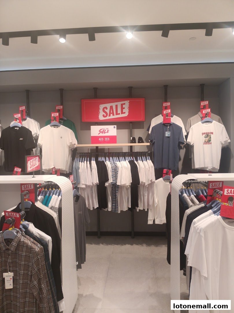 A clothing store interior with racks of t-shirts and shirts, featuring prominent "SALE" signs.