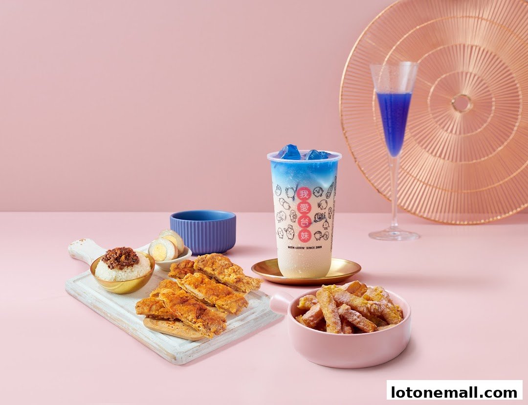 A spread of Taiwanese street food including fried chicken, rice, eggs, and fries with a bubble tea.