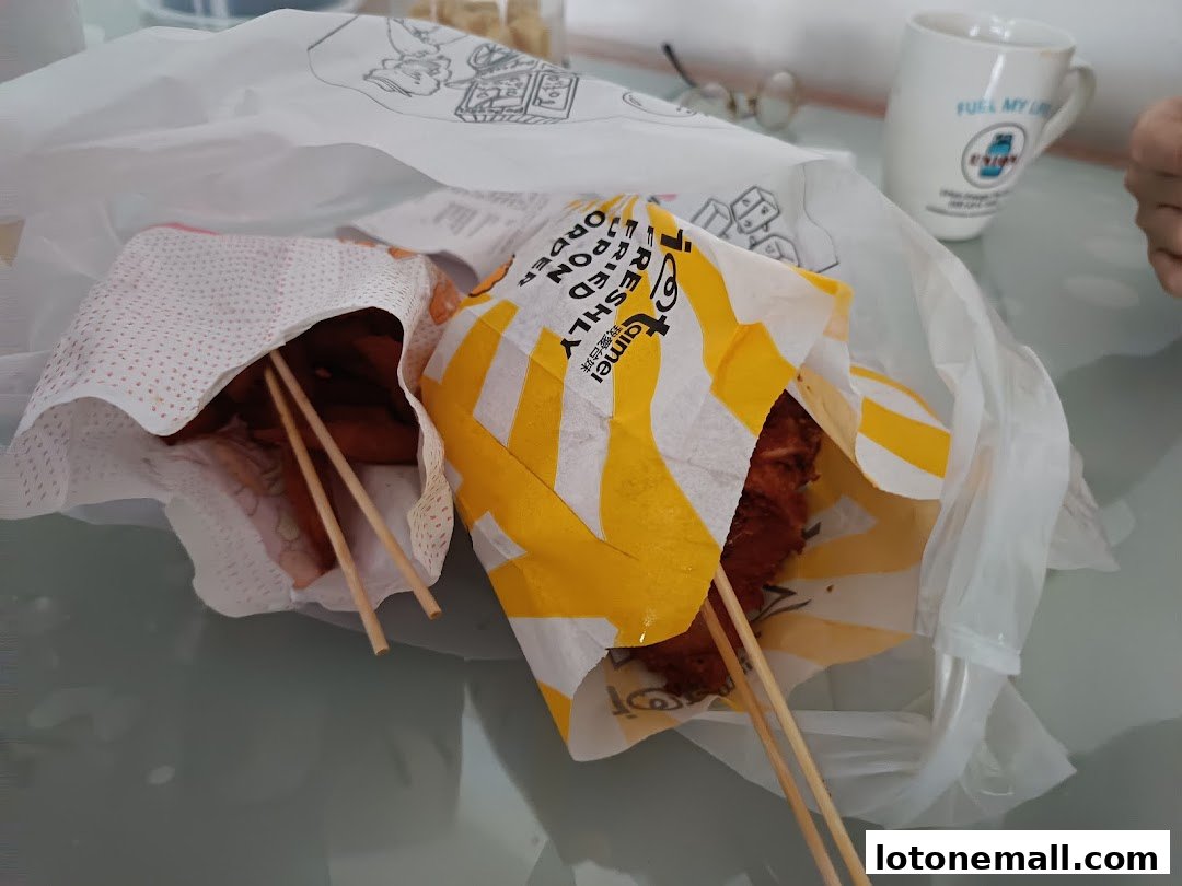 Two servings of fried food on sticks are presented in paper wrappers inside a plastic bag.