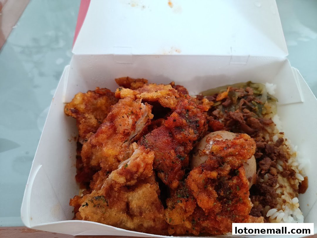A takeout box filled with crispy fried chicken, rice, and braised egg.