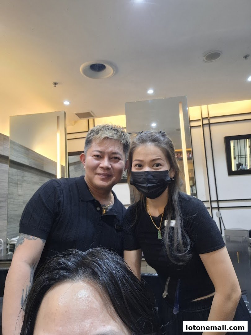 Two hairdressers pose with a client in a salon.