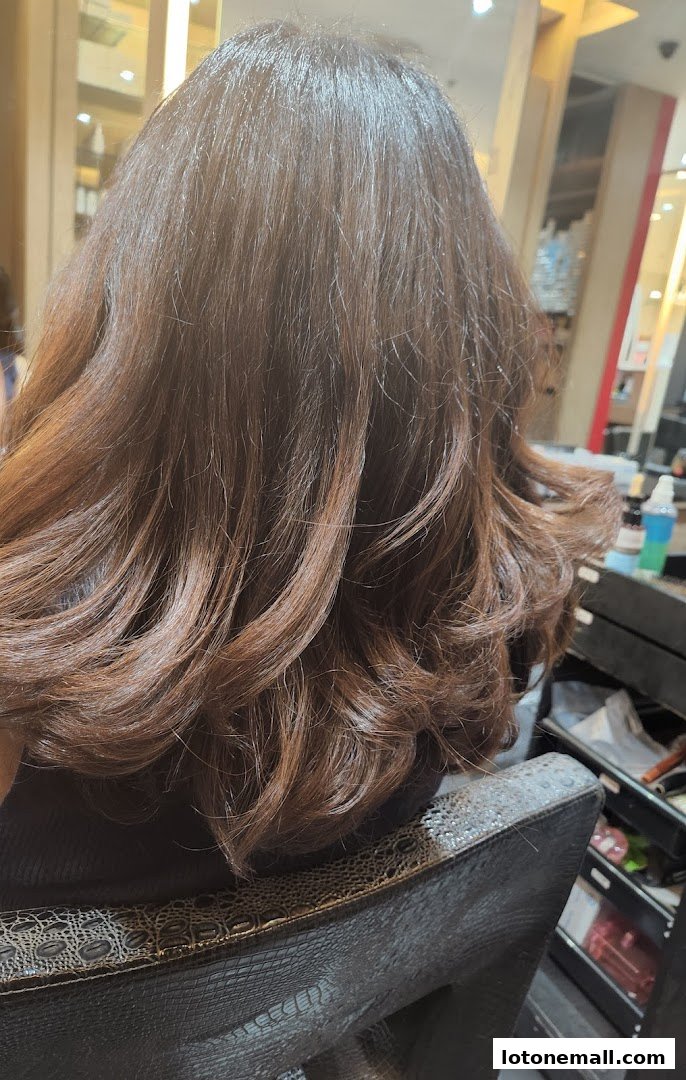 A person's freshly styled brown hair with soft waves in a salon.