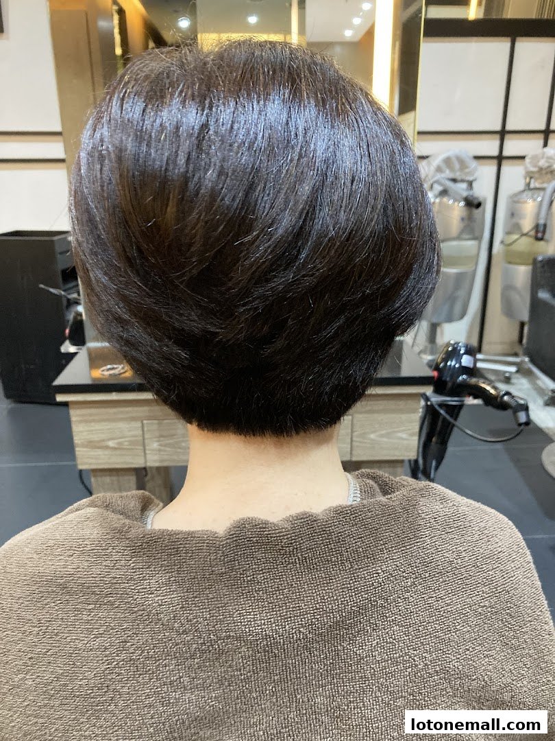 Back view of a person with a freshly styled short haircut in a salon.