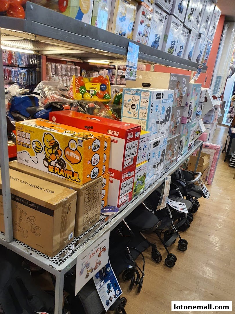 A retail store aisle filled with baby products, including strollers, toys, and booster seats.