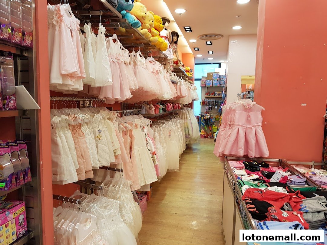 A well-lit store aisle filled with racks of children's dresses and toys.