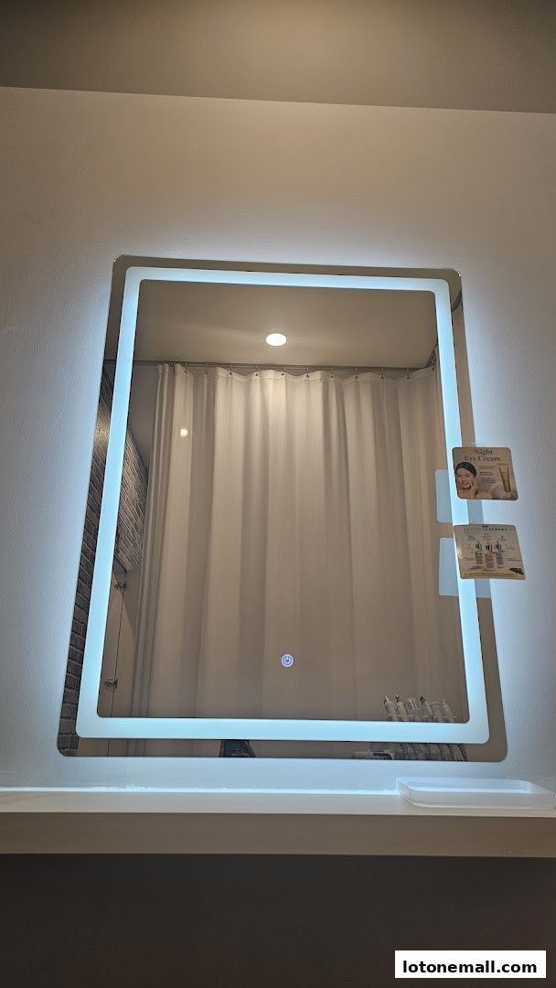 A brightly lit mirror with product displays and a white curtain in the reflection.