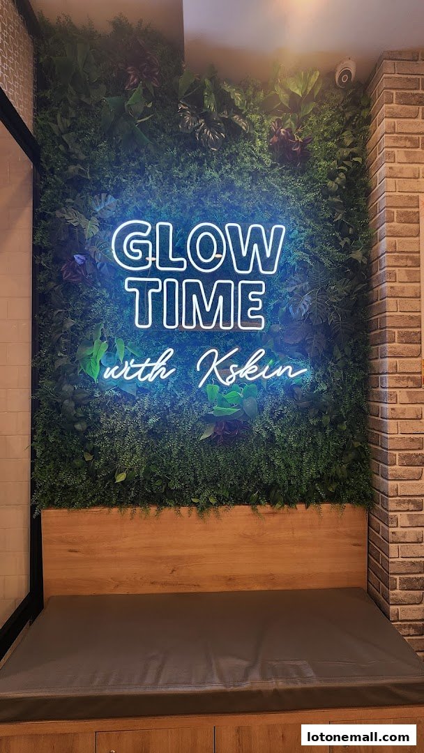 A neon sign reading 'GLOW TIME with Kskin' is displayed on a green wall with plants.