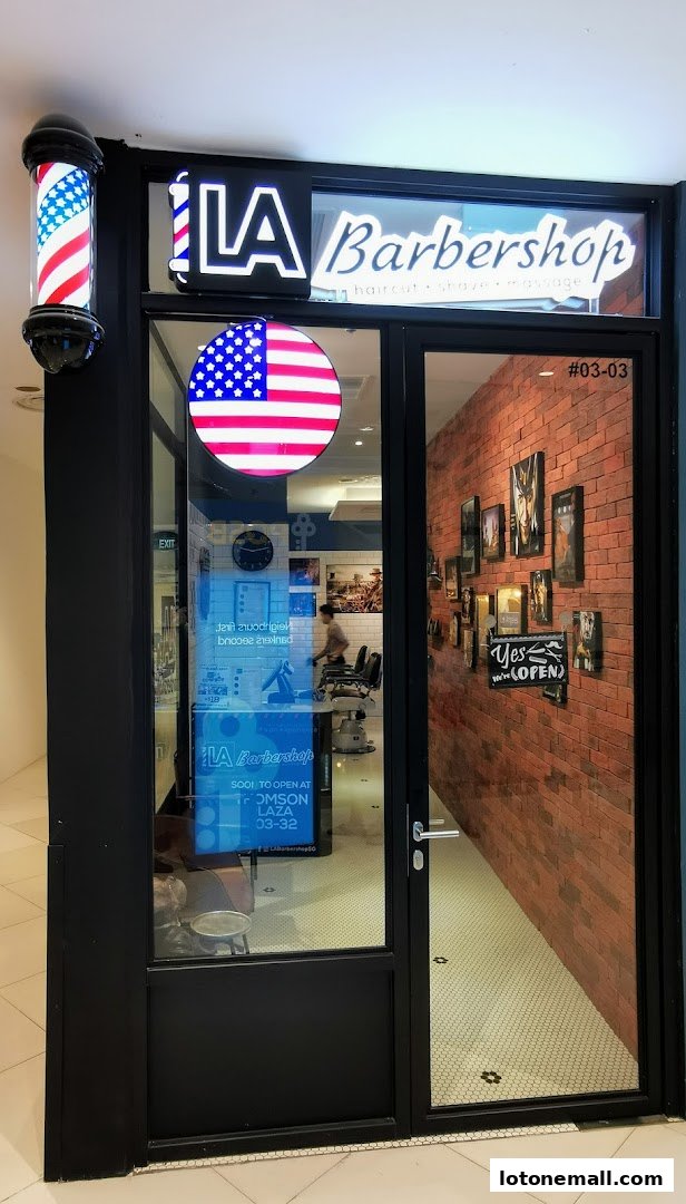 Exterior of LA Barbershop with a barber pole, American flag motif, and brick interior visible.