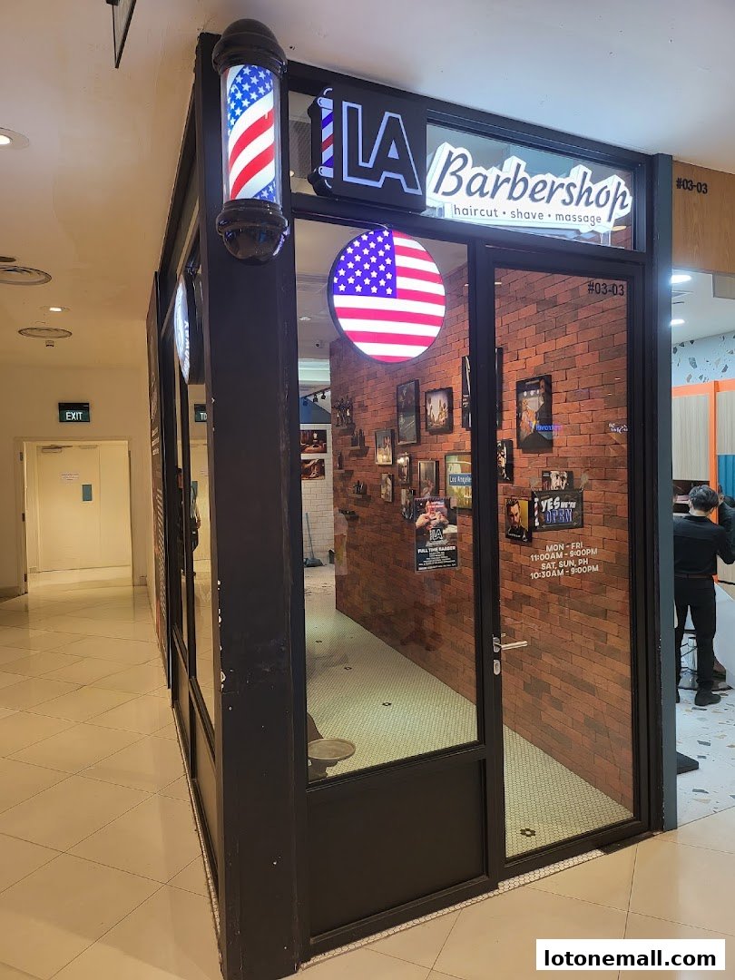 Exterior of LA Barbershop with a barber pole and American flag signage.