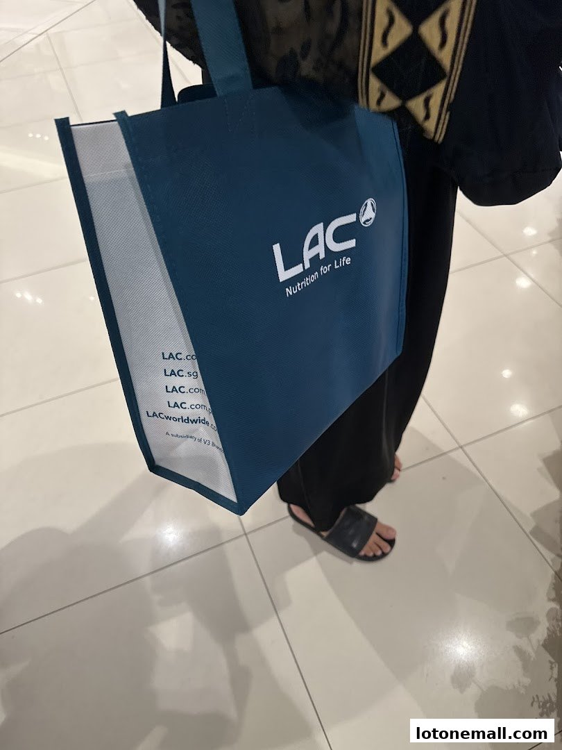 A person holds a dark blue tote bag with the LAC Nutrition for Life logo and website addresses.