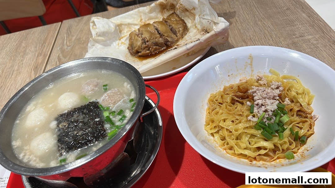 A close-up of a meal featuring noodles, soup with meatballs, and salt-baked chicken.