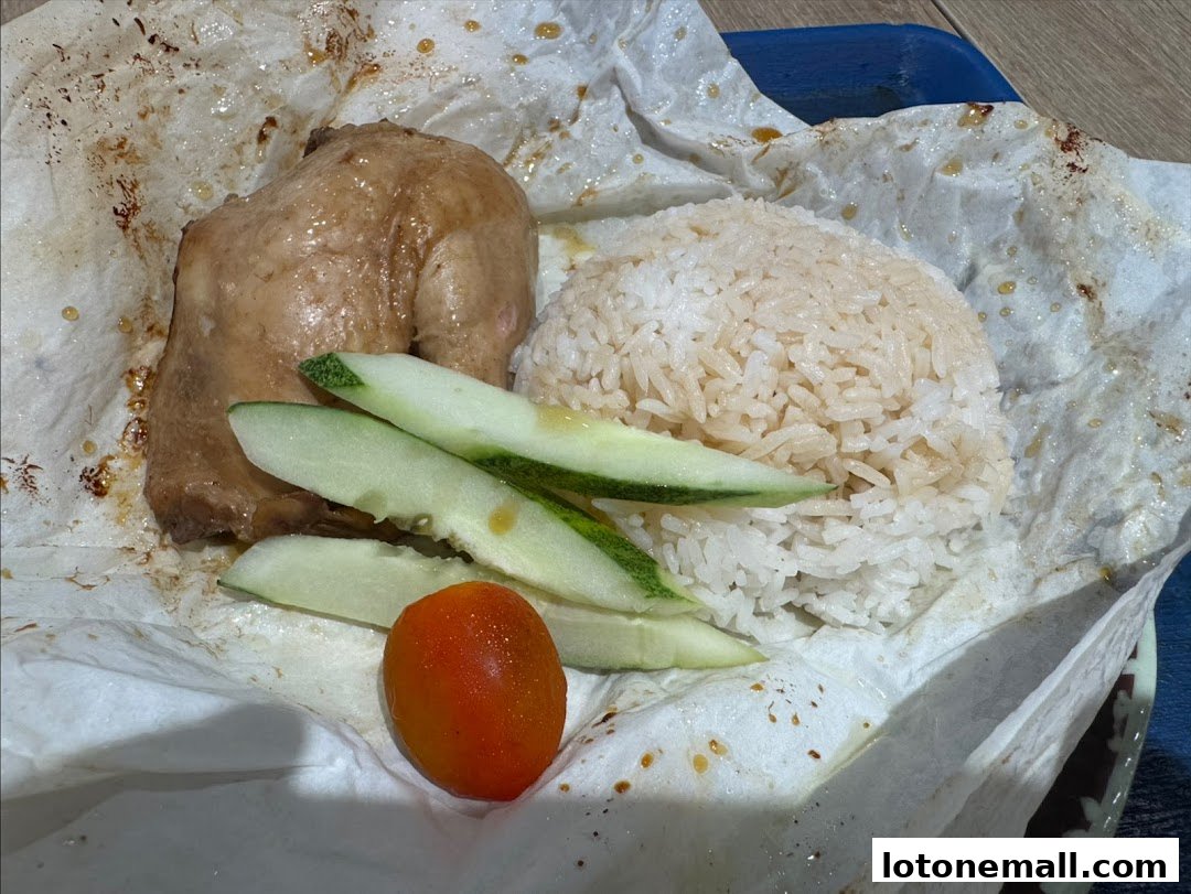A close-up of salt-baked chicken with rice, cucumber slices, and a cherry tomato.