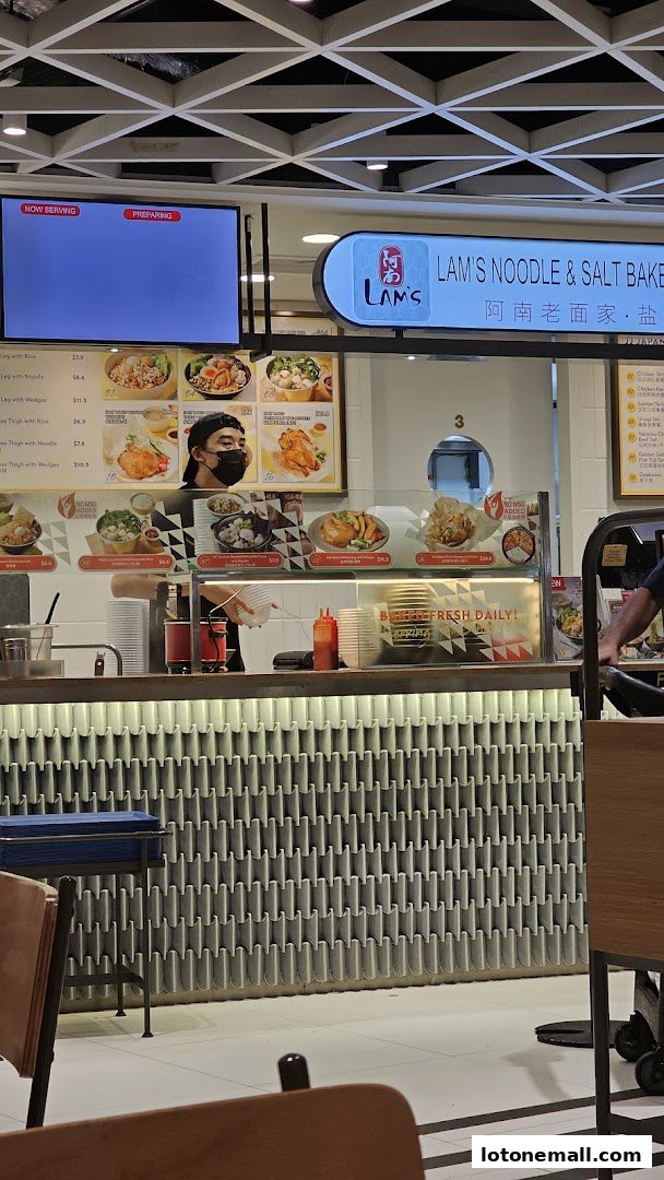 A food stall counter with a menu board displaying noodle and chicken dishes.