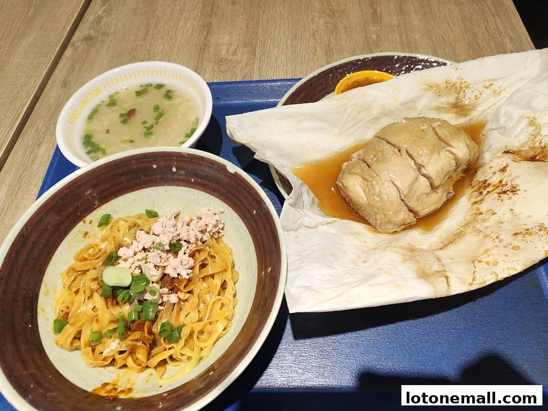 A bowl of noodles, salt baked chicken, and soup are presented on a blue tray.