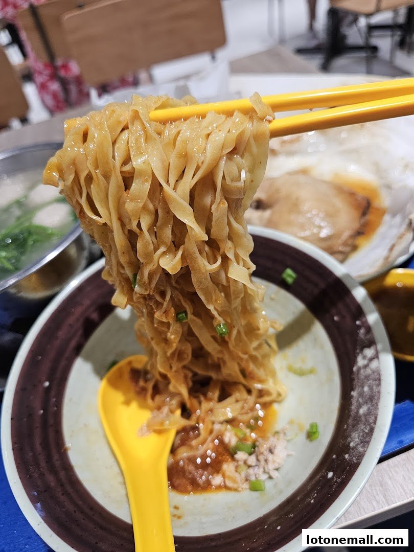 A close-up shot of delicious noodles being lifted with chopsticks from a bowl.