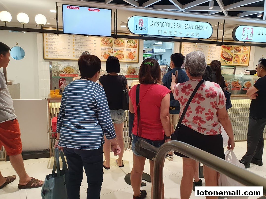 People queuing at Lam's Noodle & Salt Baked Chicken stall in a food court.