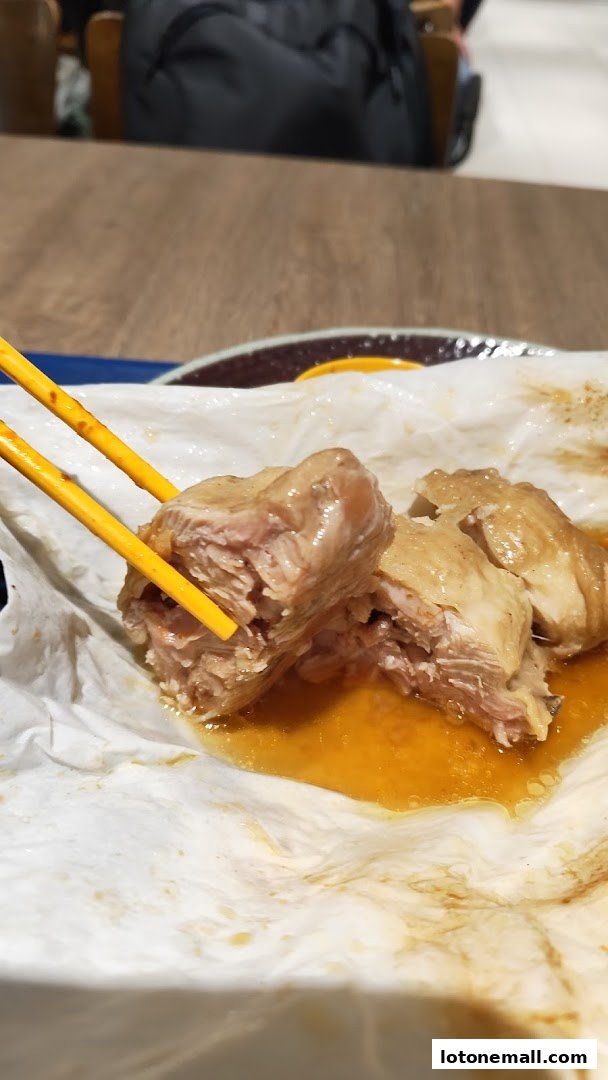 Close-up of tender salt-baked chicken being picked up with chopsticks.