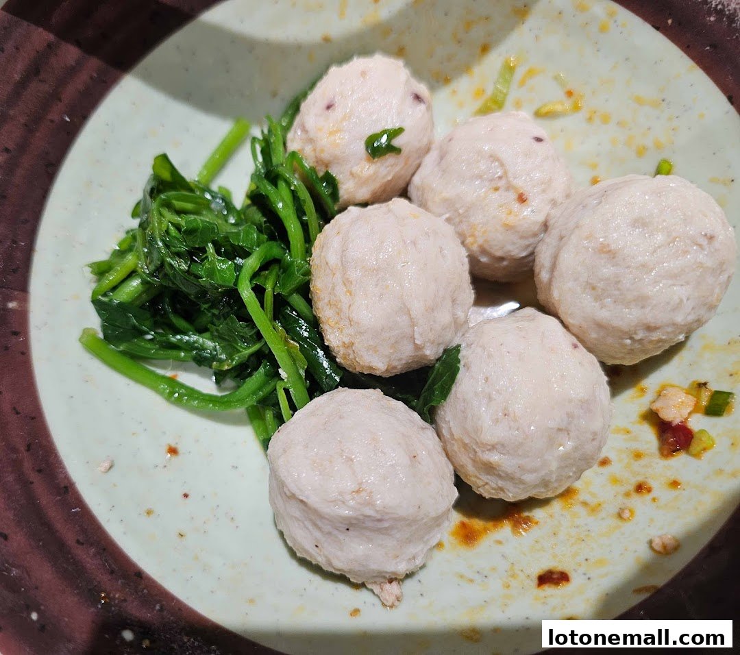 A close-up shot of a plate of fish balls served with blanched green vegetables.