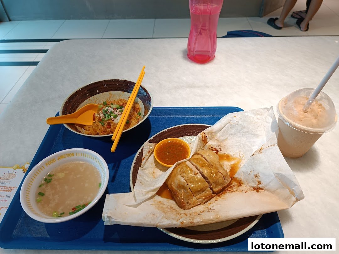 A tray of food including noodles, salt baked chicken, soup, and a drink.