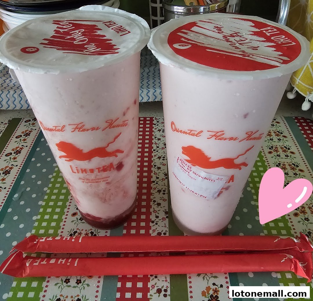 Two strawberry yogurt drinks from LiHO TEA with red straws and a pink heart.