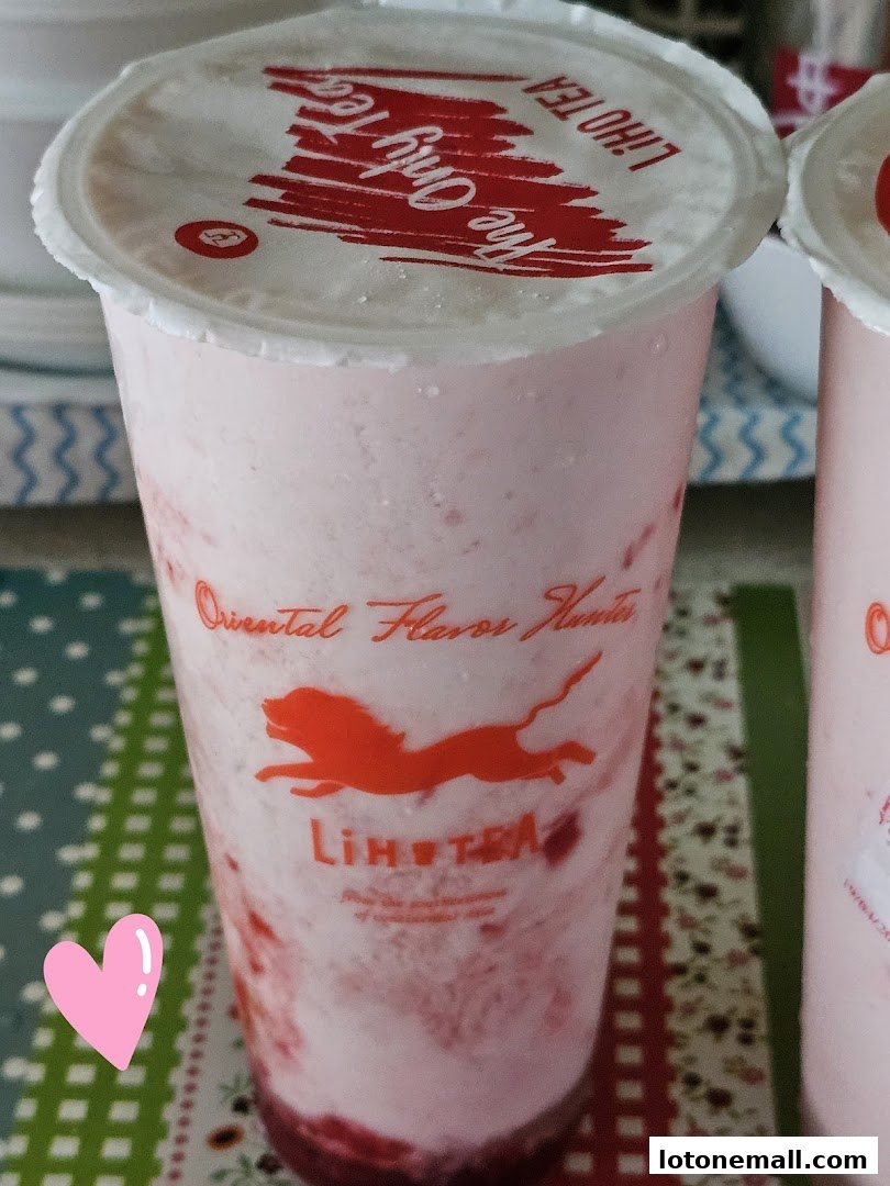 A close-up of a pink strawberry-flavored drink from LiHO TEA with a heart sticker.