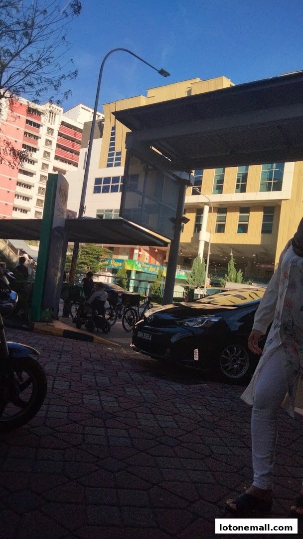 A taxi stand area with a car, bicycles, and people under a shelter.