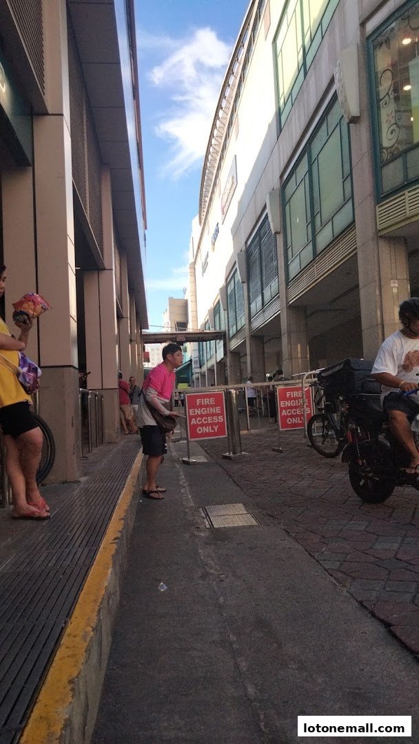 People waiting near a taxi stand with 'Fire Engine Access Only' signs.