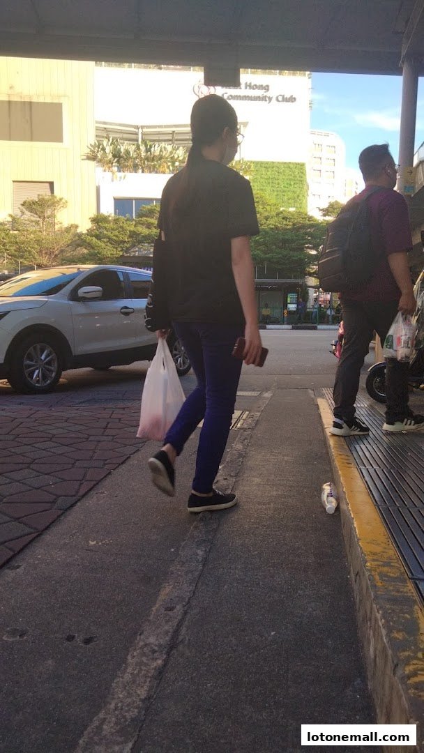 People walking on a sidewalk with a car and buildings in the background.