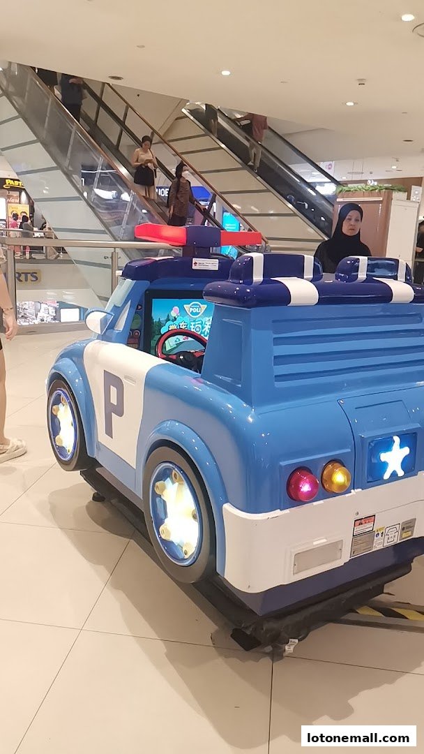 A blue and white police car kiddie ride with flashing lights in a shopping mall.