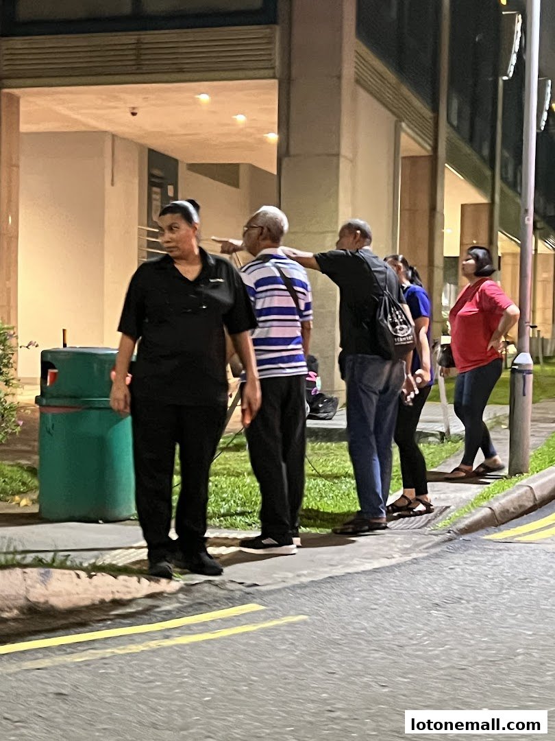 People standing outside a building at night, with one person pointing.