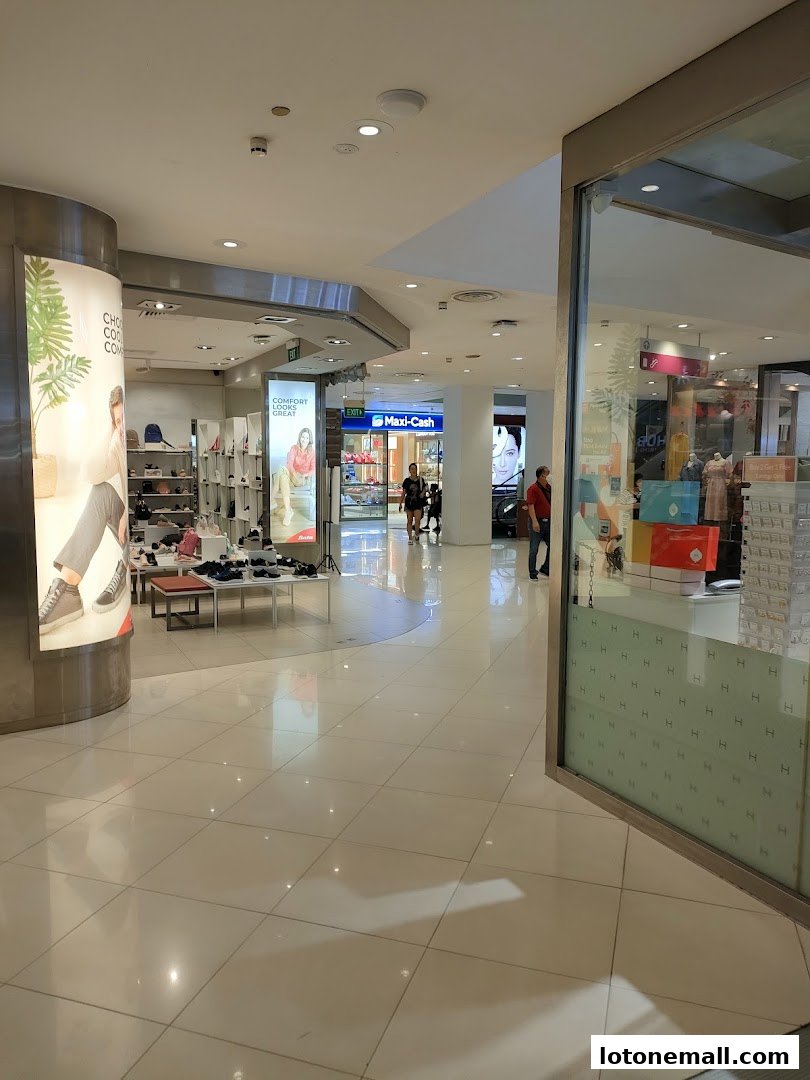 Interior view of a shopping mall with shops and displays, including a shoe store.