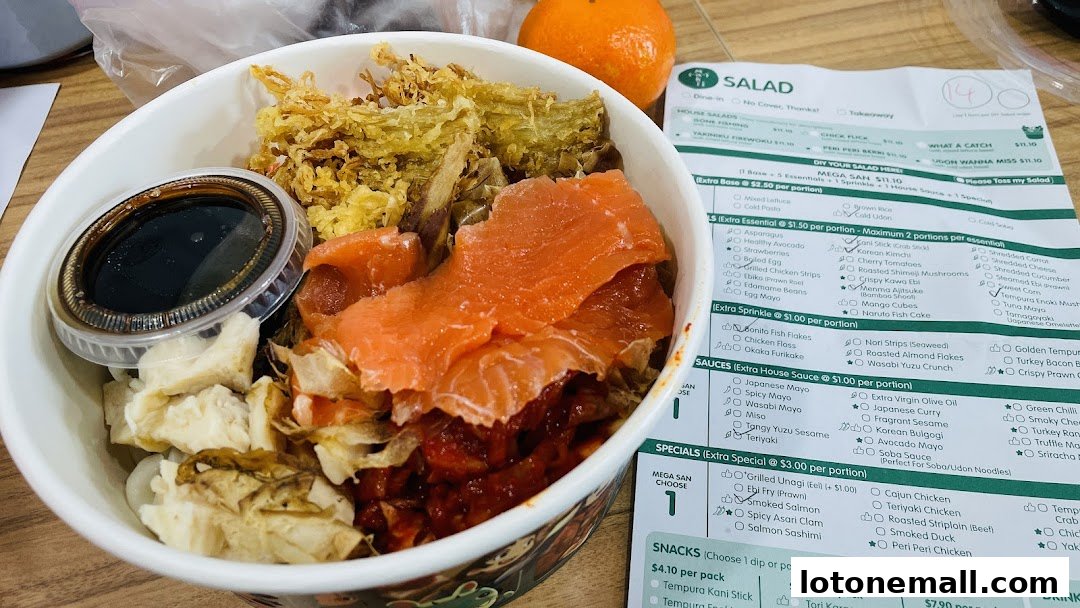 A close-up of a salmon salad bowl with a menu from Maki-San CCK Lot One.