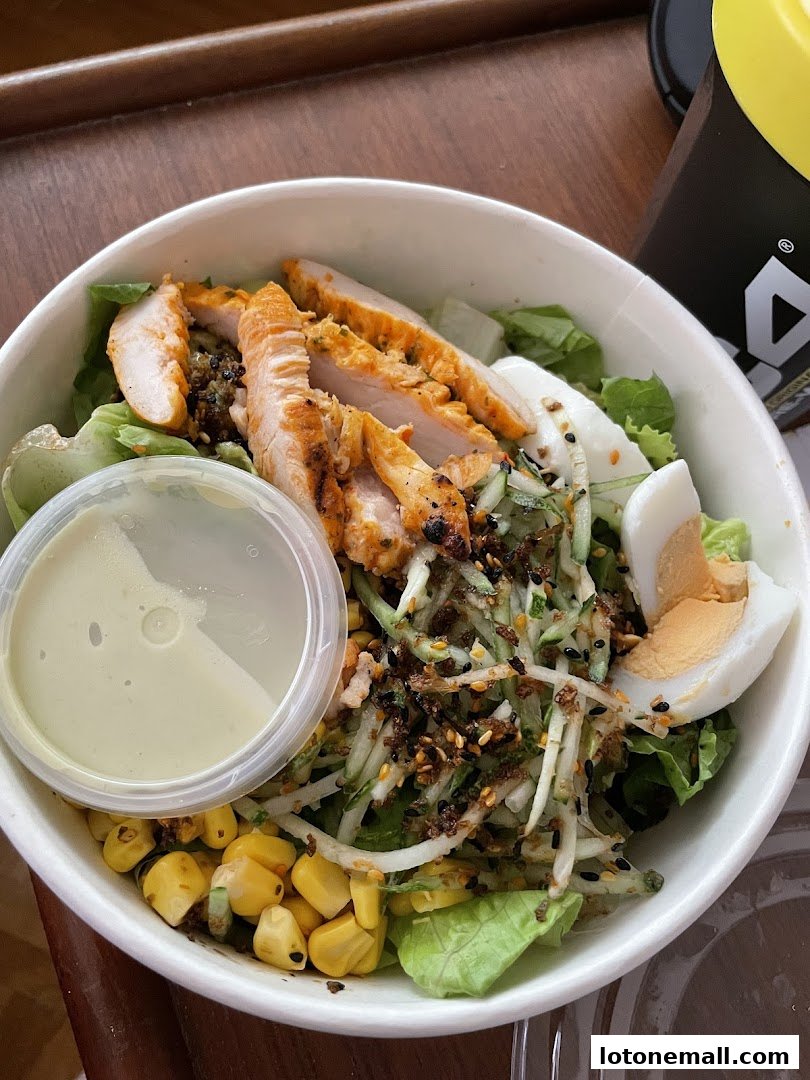 A healthy and delicious salad with grilled chicken, corn, egg, and cucumber.