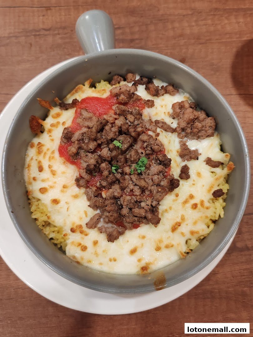 A close-up shot of a delicious dish with rice, melted cheese, tomato sauce, and ground meat.