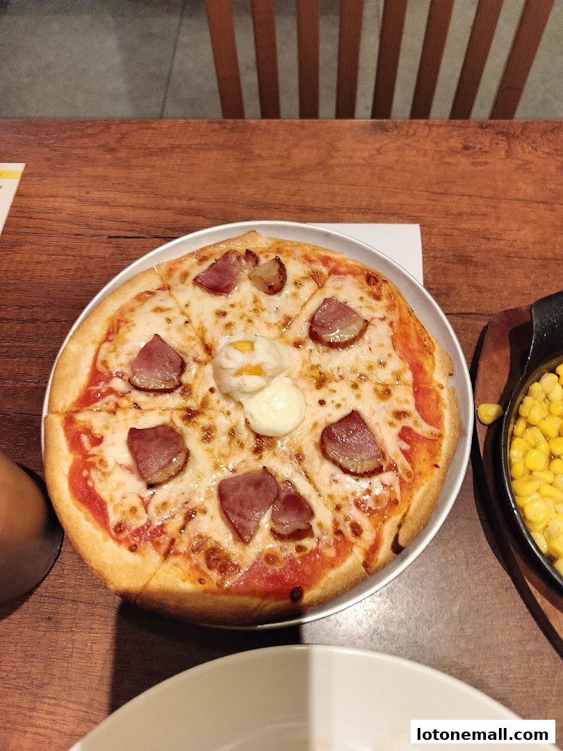 A delicious pizza with bacon and a poached egg sits on a wooden table.