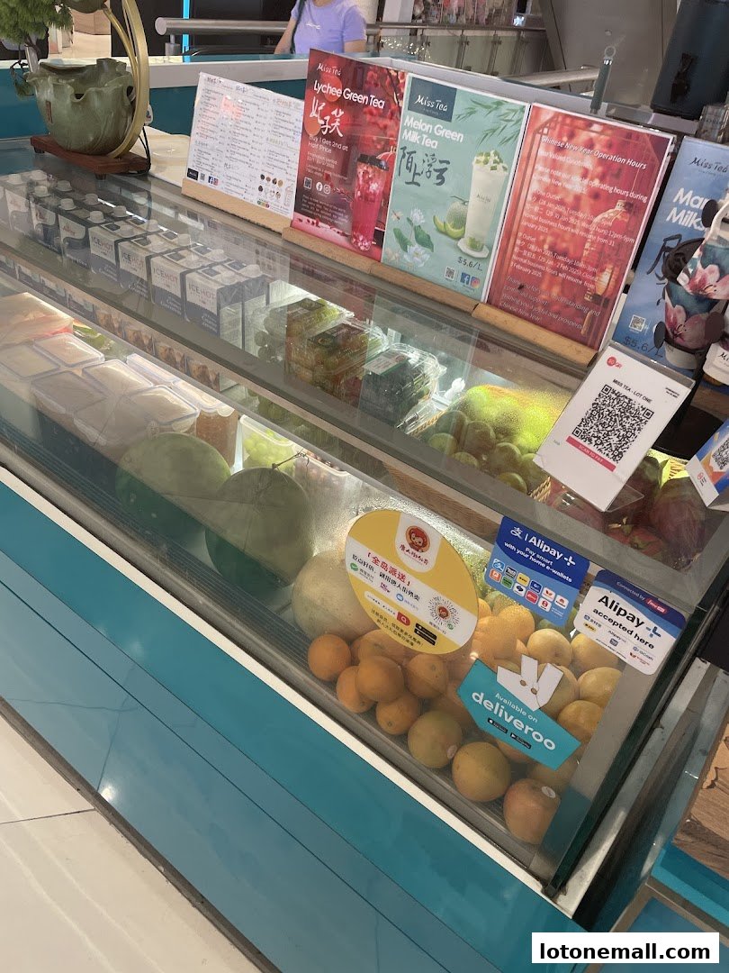 A display case filled with fresh fruits and beverages at a shop called Miss Tea.